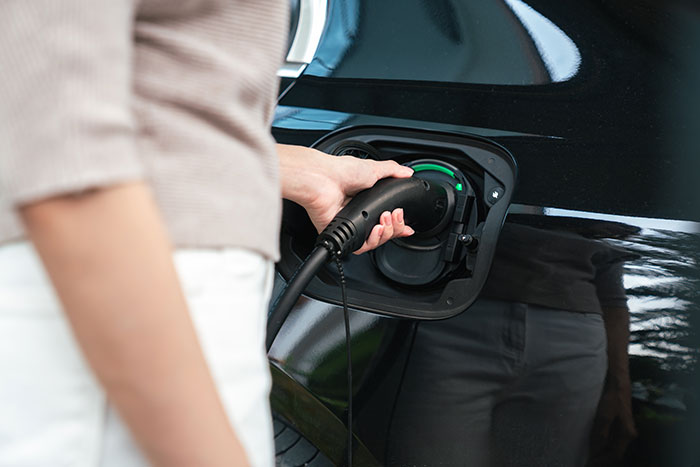 Person plugging EV charger into black electric vehicle.